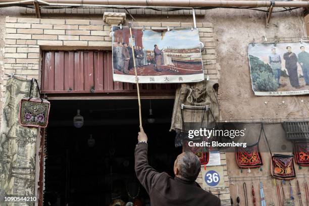Vendor hangs a copy of the painting "The Founding Ceremony of the Nation," depicting Mao Zedong inaugurating the People's Republic of China, at a...