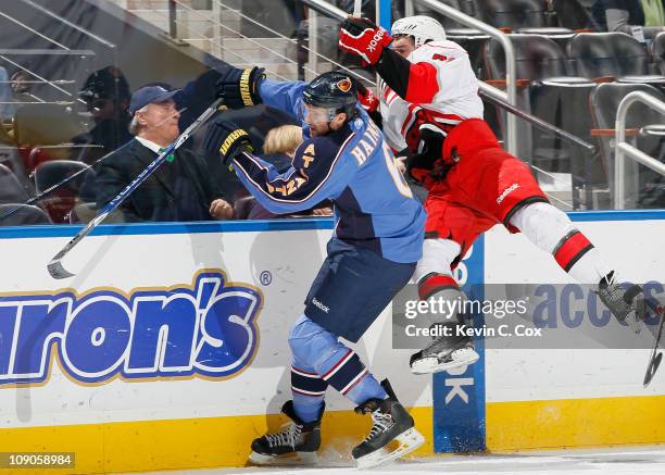 Ron Hainsey of the Atlanta Thrashers checks Jerome Samson of the Carolina Hurricanes into the boards at Philips Arena on February 13, 2011 in...