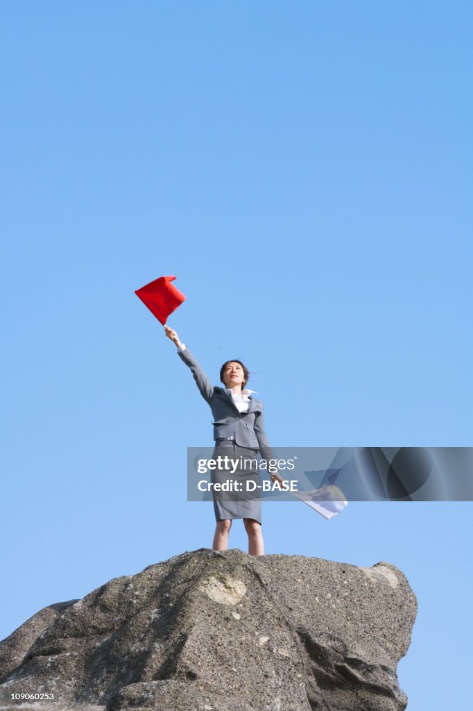 Businesswoman doing flag signaling on the cliff