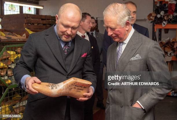 Britain's Prince Charles, Prince of Wales reacts as he is shown the size 22 shoe last made for US Basketball player Shaquille O'Neal, during his...