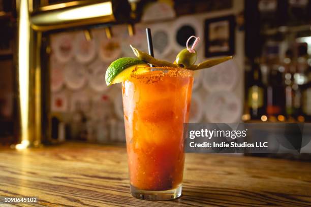 a tall cool back lit bloody mary drink sits on a wood bar counter - horizontal - bloody mary stock pictures, royalty-free photos & images