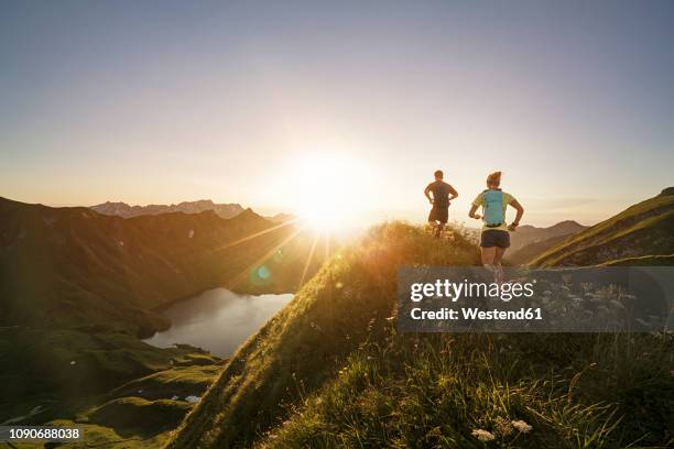 germany, allgaeu alps, man and woman running on mountain trail - dedicación fotografías e imágenes de stock