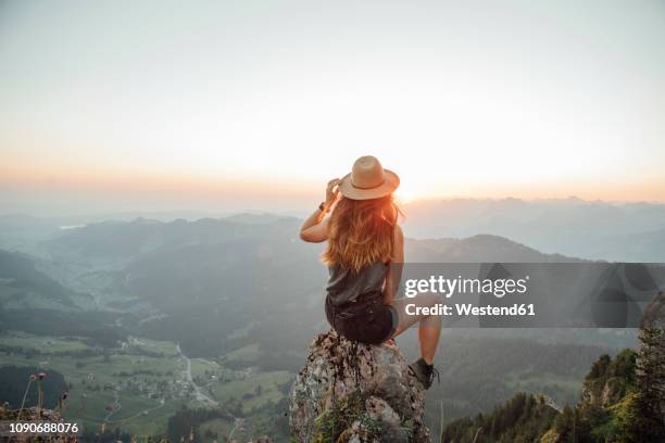 switzerland, grosser mythen, young woman on a hiking trip sitting on a rock at sunrise - mountain and summit and one person not snow ストックフォトと画像