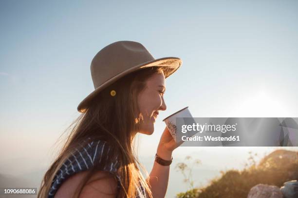 happy young woman on a hiking trip at sunrise holding a cup - coffee drink stock-fotos und bilder