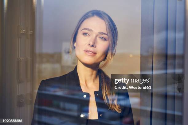 portrait of businesswoman behind windowpane - femme fenêtre photos et images de collection