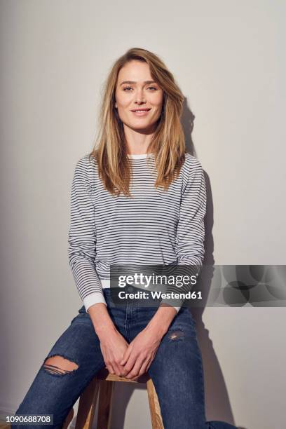 portrait of smiling woman sitting on stool - blonde photos et images de collection