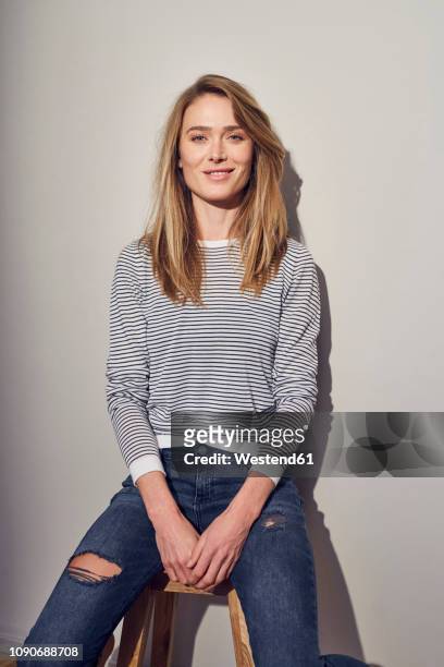 portrait of smiling woman sitting on stool - ripped jeans stock pictures, royalty-free photos & images
