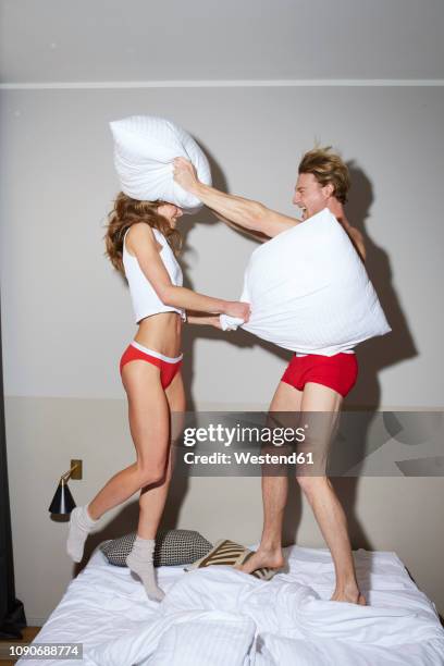 couple having a pillow fight in bed - kissenschlacht paar stock-fotos und bilder