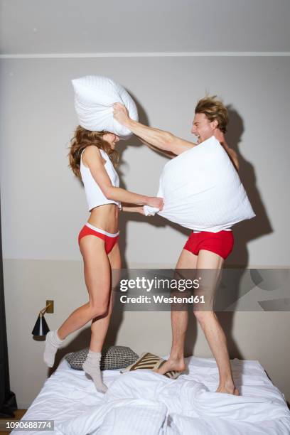 couple having a pillow fight in bed - luta de almofada imagens e fotografias de stock