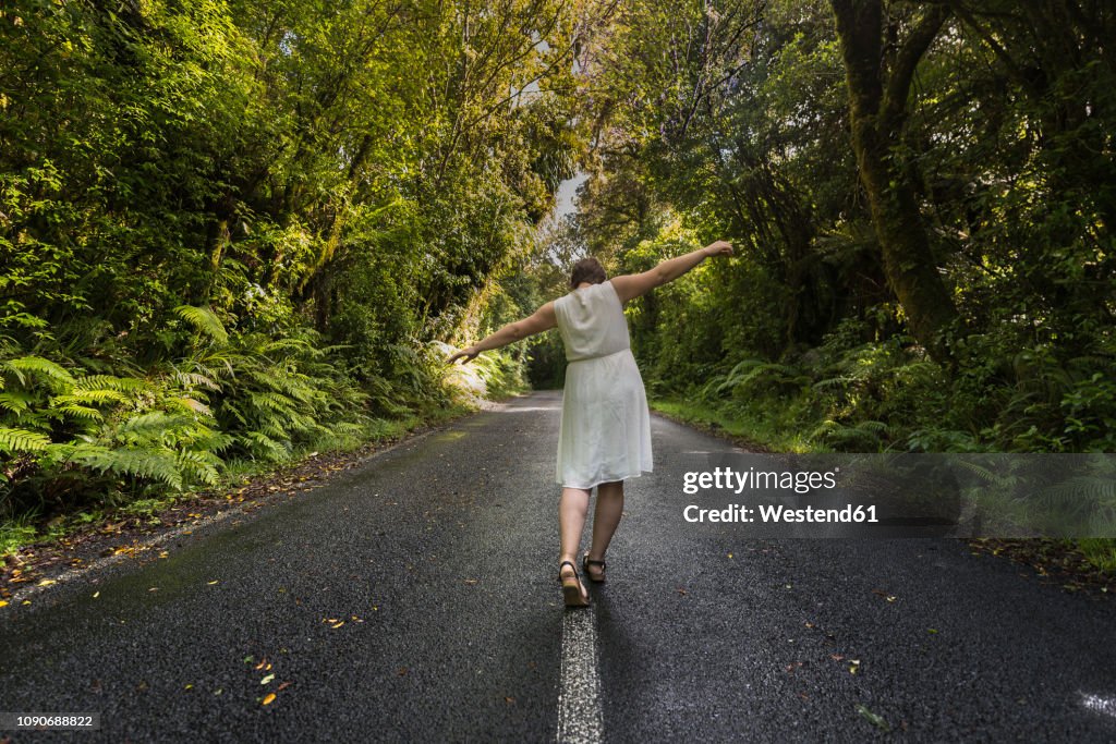 New Zealand, North Island, Egmont National Park, Woman balancing on centre line on road