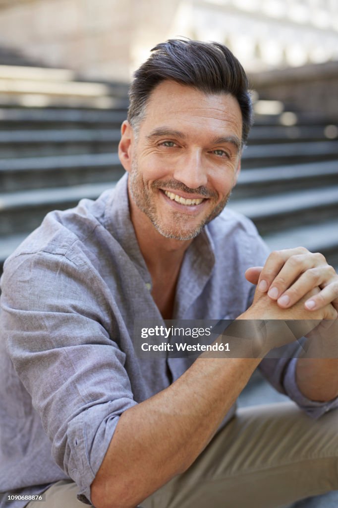 Portrait of laughing mature man   sitting on stairs