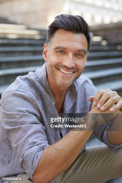 portrait of laughing mature man   sitting on stairs - handsome people stock pictures, royalty-free photos & images