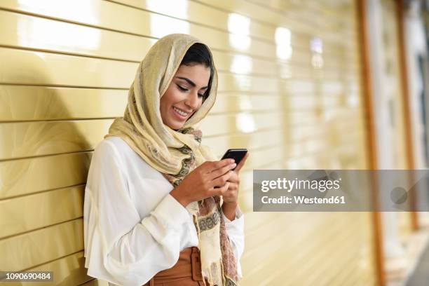 spain, granada, young arab tourist woman wearing hijab, using smartphone - arab phone stock-fotos und bilder