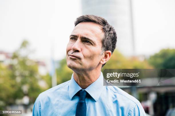 portrait of businessman in city park thinking - suspicion stock-fotos und bilder