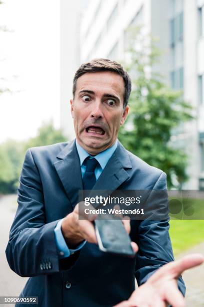 shocked businessman with cell phone in the city - panic attack stock-fotos und bilder