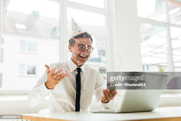 laughing businessman with laptop celebrating birthday in office - birthday office stockfoto's en -beelden