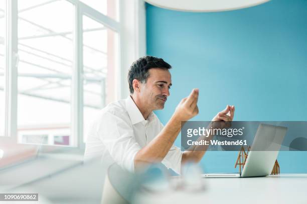 confident businessman using laptop on table in office - met de vingers knippen stockfoto's en -beelden
