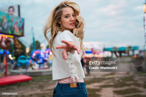 young woman on a funfair reaching out her hand - temptation stock-fotos und bilder