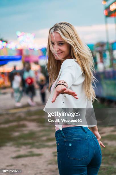 smiling young woman on a funfair reaching out her hand - sedução imagens e fotografias de stock