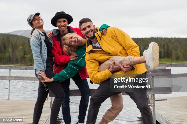 finland, lapland, portrait of happy playful friends on jetty at a lake - finland happy stock pictures, royalty-free photos & images