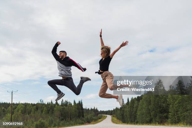 finland, lapland, exuberant young couple jumping in rural landscape - finland happy stock pictures, royalty-free photos & images