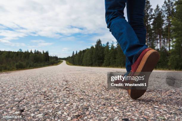 finland, lapland, feet of man walking on empty country road - shoes man stock pictures, royalty-free photos & images