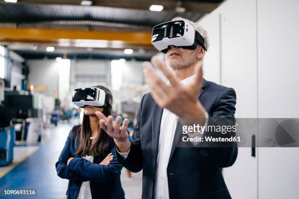 businessman an woman in high tech enterprise, using vr glasses - virtual togetherness stock pictures, royalty-free photos & images
