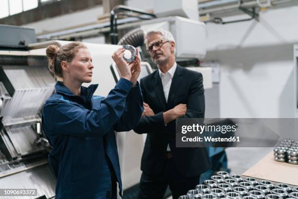 manager and skilled worker in high tech enterprise, checking machine parts - steel industry stock-fotos und bilder