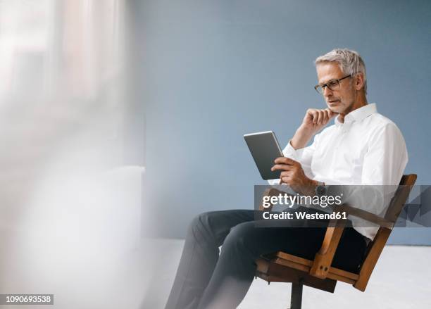 manager sitting in office, using digital tablet - executive office chair stock pictures, royalty-free photos & images