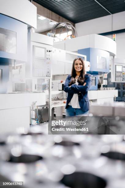 confident woman working in high tech enterprise, standing in factory workshop with arms crossed - metal workshop stockfoto's en -beelden