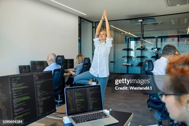 woman practicing yoga in office surrounded by busy colleagues - connected mindfulness work stock pictures, royalty-free photos & images