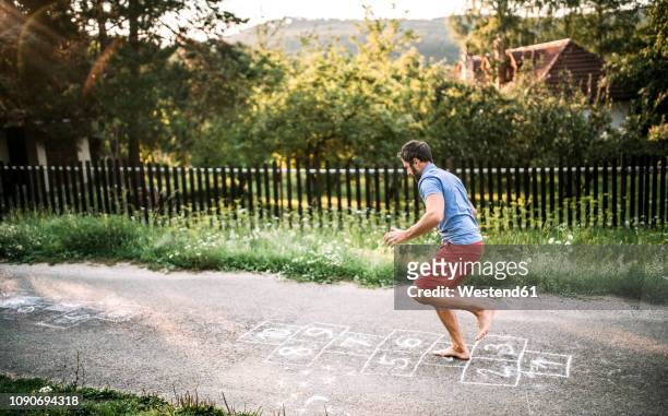 man playing hopscotch with naked feet - hopscotch stock pictures, royalty-free photos & images
