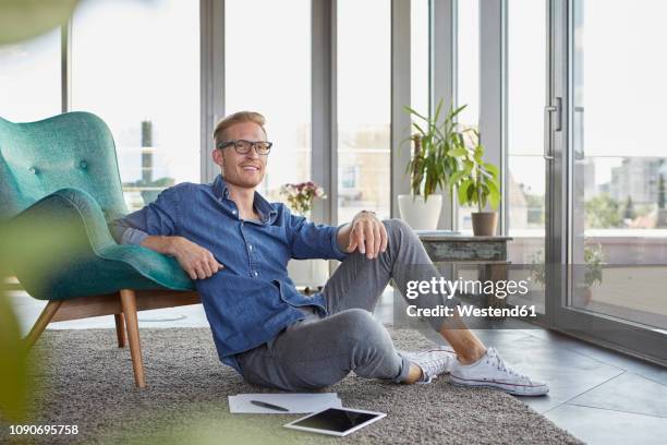 smiling young man sitting on carpet with tablet and notepads at home - entry draft portraits stock pictures, royalty-free photos & images