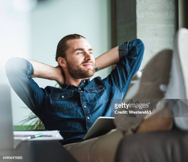 relaxed smiling businessman sitting in office looking out of window - office desk top view stockfoto's en -beelden