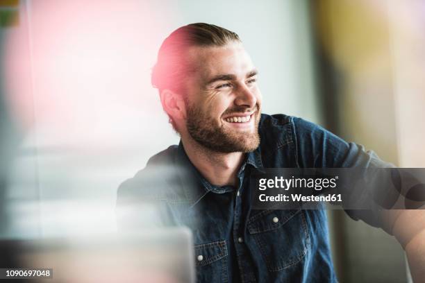 portrait of smiling young businessman in office - selective focus stock-fotos und bilder