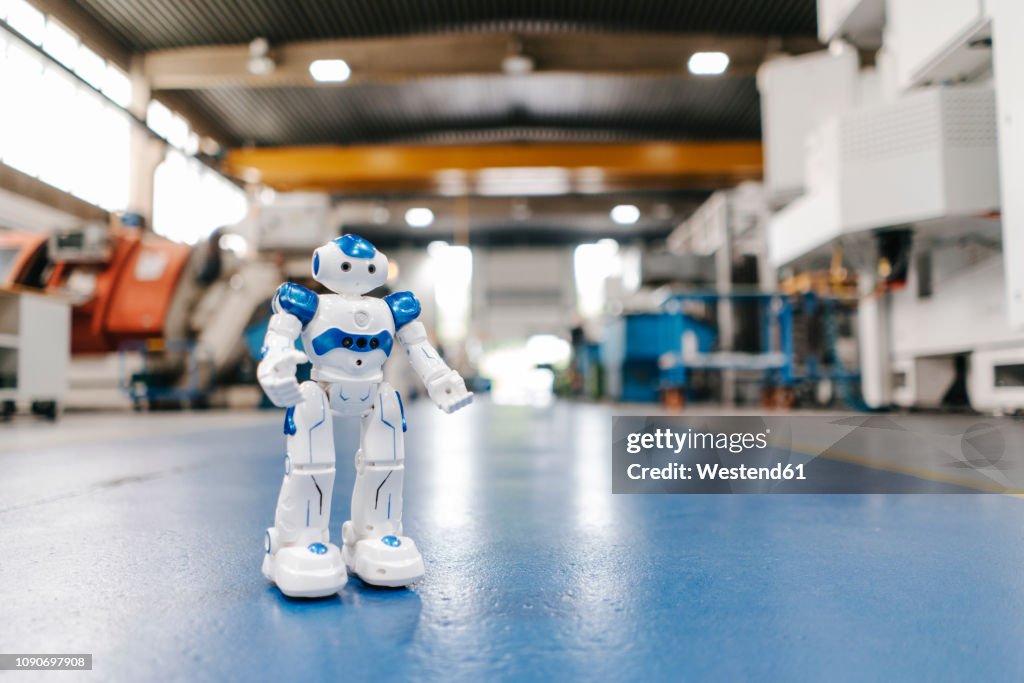 Toy robot standing on floor of factory workshop