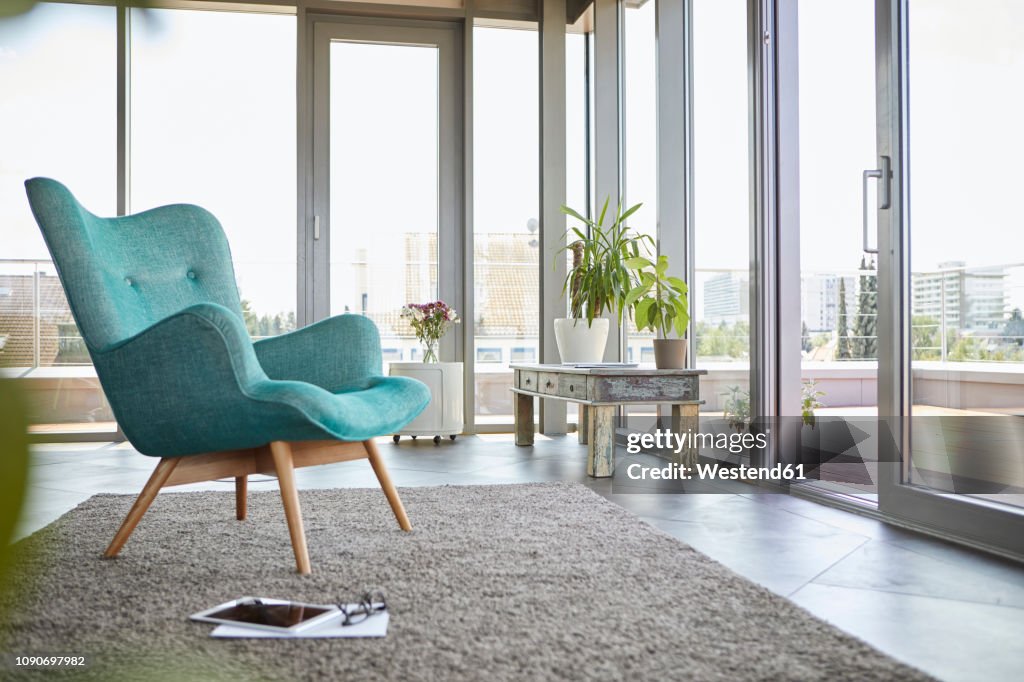 Home interior with armchair, tablet and view on roof terrace