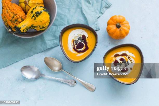 two bowls of homemade hokkaido pumpkin soup garnished with cream, pumpkin seed oil and pumpkin seed - pumpkin oil stock pictures, royalty-free photos & images