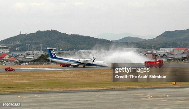 Flight 1603 is seen being splashed water after making a body landing on the runway of Kochi Airport on March 13, 2007 in Nangoku, Kochi, Japan. The...