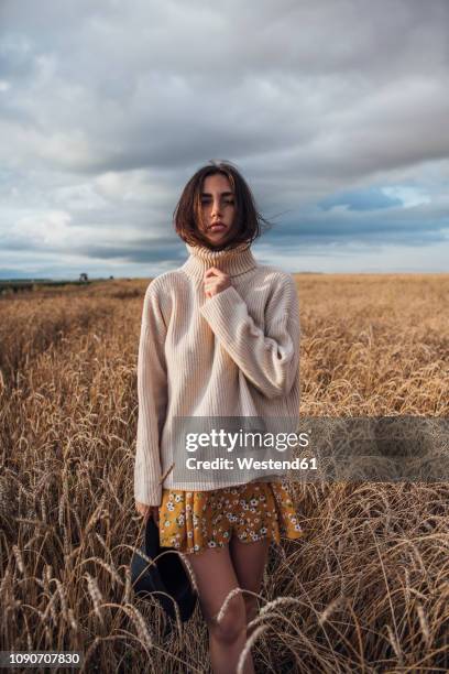 portrait of young woman wearing oversized turtleneck pullover standing in corn field - demasiado grande fotografías e imágenes de stock