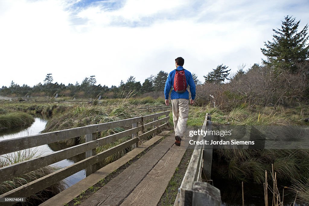 Man hiking across a bridge near the ocean.