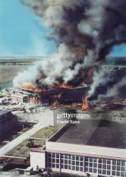 Smoke rises from the burning buildings on Ford Island, Pearl Harbor, Oahu Island, after the surprise attack by Japanese forces, which brought America...