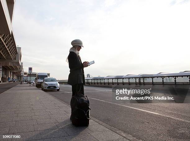 woman sends message on digital tablet, outside airport - milan airport stock pictures, royalty-free photos & images