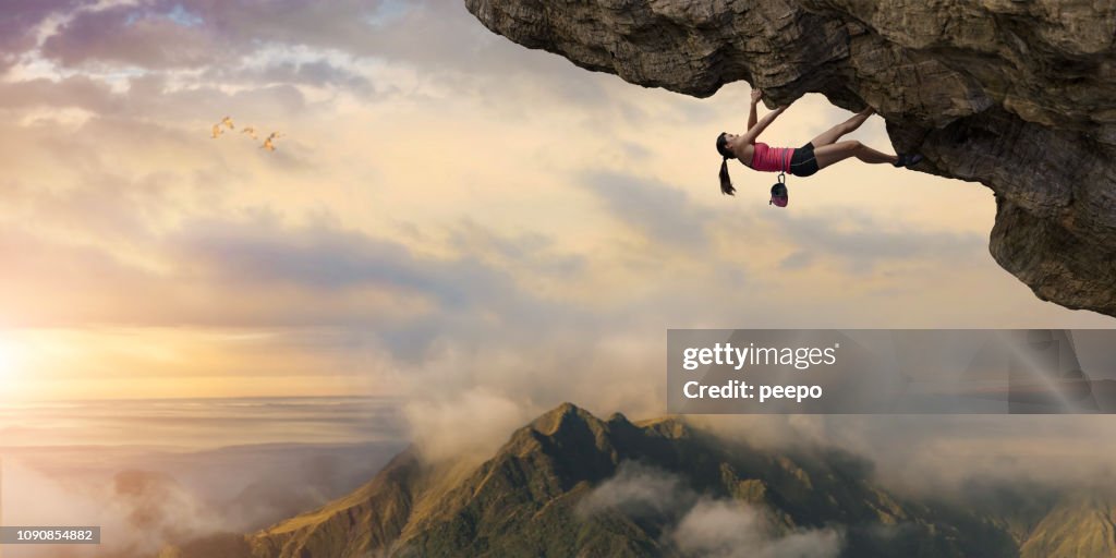 Woman Free Climber Climbs Overhang High Above Mountains at Dawn