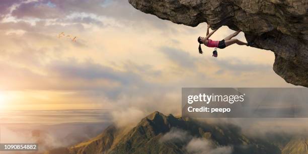 woman free climber climbs overhang high above mountains at dawn - extreme sports women stock pictures, royalty-free photos & images