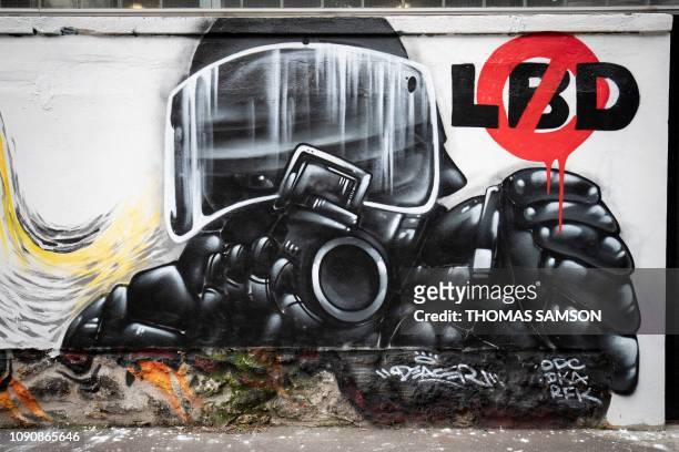 Picture taken in Paris on January 29 shows a mural depicting a riot police officers aiming with a rubber bullets less lethal gun and the words LBD,...