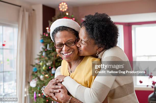 mom and adult daughter hugging at christmas tree - family 2010 foto e immagini stock