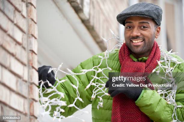 smiling man with strand of christmas lights - versierd jak stockfoto's en -beelden