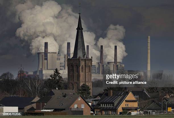 January 2019, North Rhine-Westphalia, Elsdorf: Smoke and steam rise from the RWE lignite-fired Neurath power station behind the St. Martinus church...