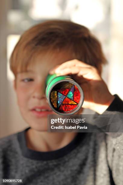 boy looking through kaleidoscope - kaleidoscope pattern stock pictures, royalty-free photos & images